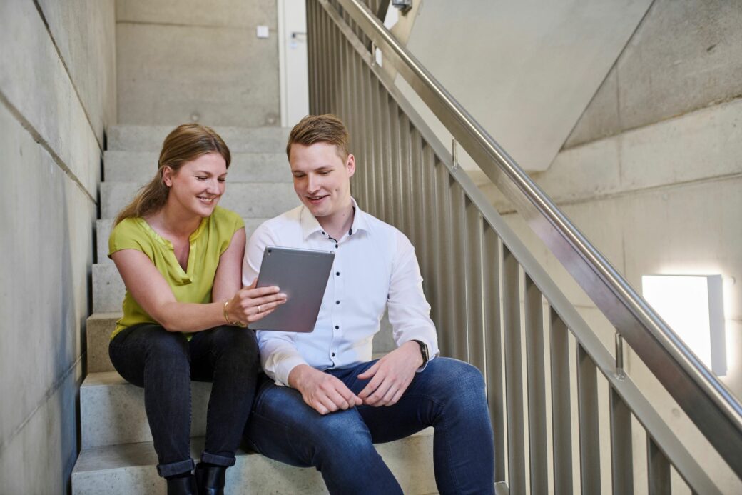 Zwei Mitarbeitende sitzen zusammen und tauschen sich über das Onboarding aus.