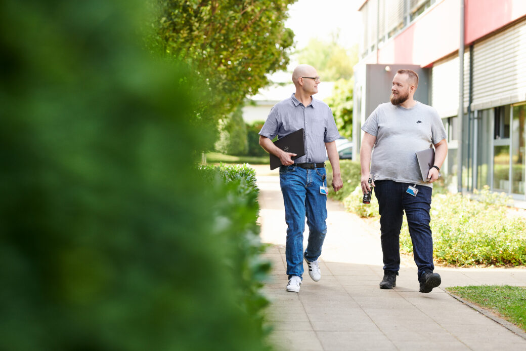 Mitarbeitende aus der Development unterhalten sich bei einem Spaziergang über ihre Arbeit